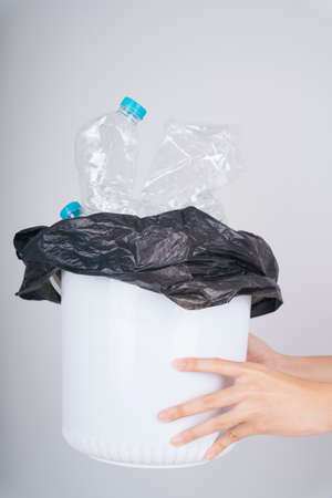 Woman hand holding trash rubbish bin full of plastic bottle isolate over white background.