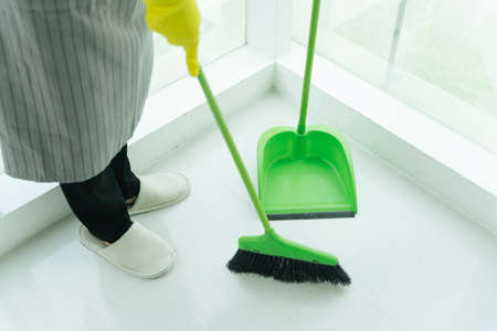 Maid house cleaning floor with bloom and dustpan. Covid-19 Coronavirus prevention.