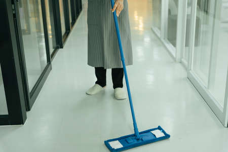 Maid using mop cleaning the floor in condo apartment room.の写真素材