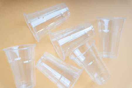 Group of transparent plastic cups over beige background.の写真素材