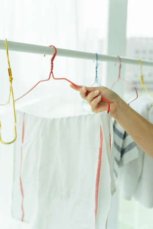 Maid woman hanging cloth after laundry on a rack.