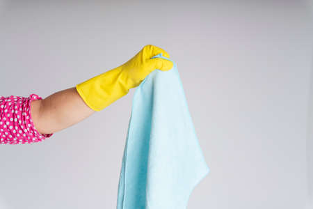 Cleaner hand wearing yellow protective glove holding blue rag cloth isolate over white background....