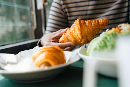 Cropped image of a man's hand, he give a croissant thumb down because it's unhealthy.の写真素材