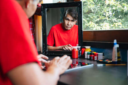 Reflection in a mirror of old man while he use tablet for social media.