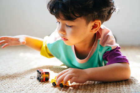 Little boy lie down on the stomach on the floor and playing car toy.の写真素材