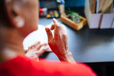 Over shoulder shot of old man's hand over the book while he reading the book in his free time.の写真素材
