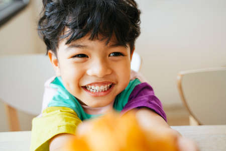 Little boy hold the sausage croissant in his hands with smile of happiness on his face.の写真素材