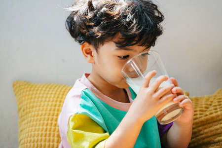 Little boy enjoy drinking the milk in clear glass with happiness.の写真素材