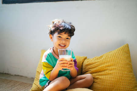Little boy enjoy drinking the milk in clear glass with happiness.の写真素材