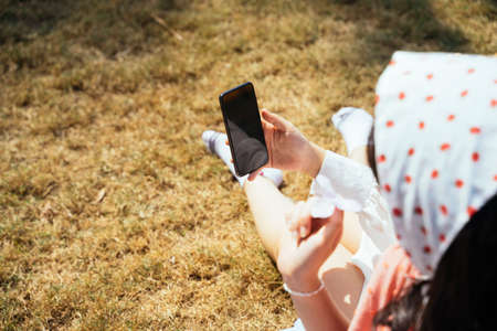 Two girls sitting back to back on the mat on the field, play the bubble andpurple flowers.