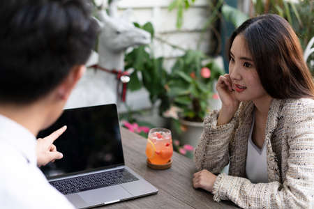 Young asian business people talking about business, looking at presentation on laptop.