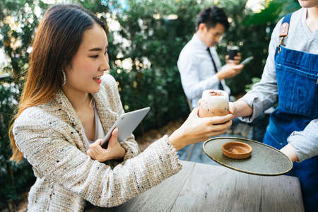 Asian thai businesswoman order ice cold coffee milk from waitress at coffee shop.の写真素材