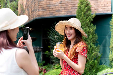 Two young beautiful asian women wearing hat on vacation. Travel together at resort.の写真素材