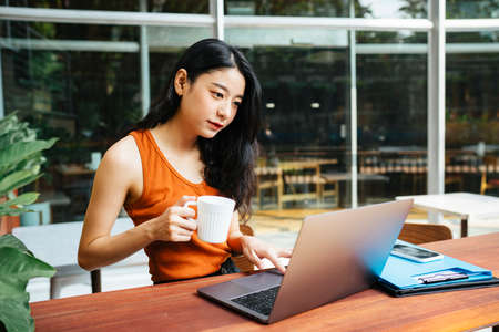 Asian beautiful woman wearing orange shirt talking to someone at coffee shop cafe.の写真素材
