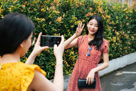 Beautiful asian woman wearing red dress eating street food with friend on yellow dress together on the street - Street food.の写真素材