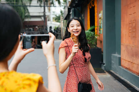 Young beautiful Thai asian traveler woman wearing red dress and hat closed eyes raising hands at river pier.の写真素材