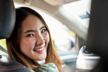 Cheerful happy thai woman smiling at rear mirror in the car.の写真素材