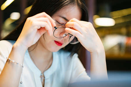 Beautiful asian woman wearing red dress and hat holding smartphone looking lost in the city, walking into travel guide staff.の写真素材