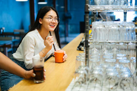 Beautiful asian woman wearing red dress and hat holding smartphone looking lost in the city, walking into travel guide staff.の写真素材