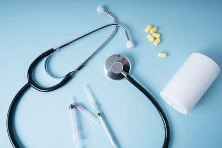 Doctor background - Stethoscope and medicine pills with syringe over blue background.の写真素材