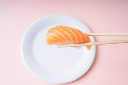 Fresh salmon sushi on white plate eating with chopstick over pink background.の写真素材