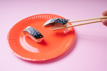 Human using chopstick eating saba sushi on red plate.の写真素材