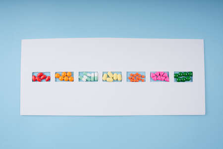 Top view - Colourful pills medicine in small frame on white paper.
