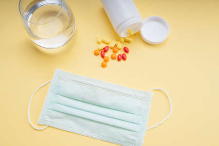 Top view - Doctor mask and water glass with medicine pills from white bottle box.の写真素材