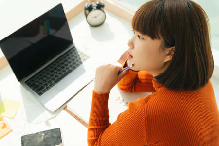 Beautiful young asian thai black short hair woman thinking new concept idea while work from home at...