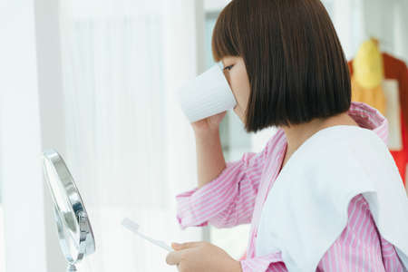 Young asian thai bob hairstyle woman brushing teeth with toothbrush in restroom.の写真素材