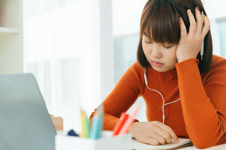 Beautiful young asian thai black short hair woman learning from home study online on laptop and...