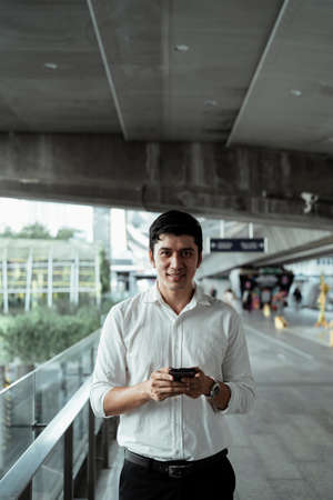 Mature asian business man on white formal shirt using smartphone on the street.の写真素材