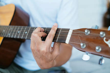 Cropped image of musician's hand put on the fretboard and neck while playing.
