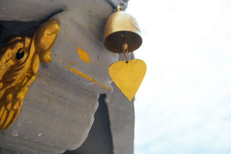 Close up shot of small bell at the end of concrete dragon with the sky as a background.の写真素材