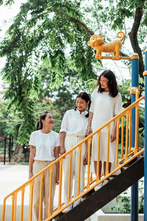 Triple twin sister standing on the ladder of toy in the playground.