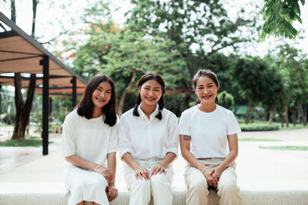 Triple twin sister sitting on the marble bench at the playground in the park.の写真素材