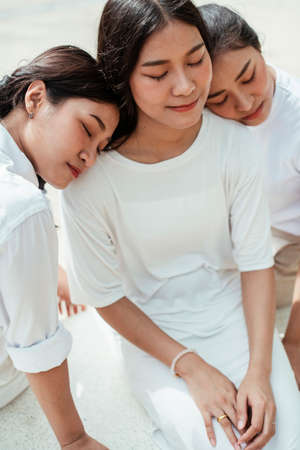 Triple twin sister sitting on the marble bench at the playground in the park.の写真素材