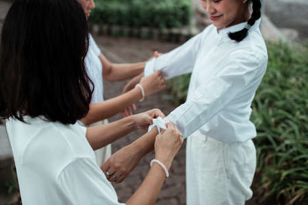 Two twin sister roll the shirt's sleeve for a pigtails girl in the park.の写真素材