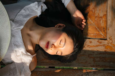 Flat lay - Asian young woman on white shirt sleeping on wooden old floor.の写真素材