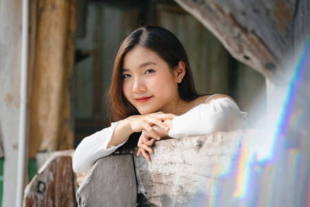 Young thai woman looking out at wooden balcony at hotel. Pretty asian woman at old house.