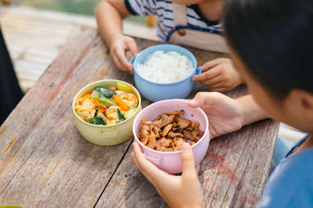 Two little asian woman eating food in thai container box or Pinto.の写真素材
