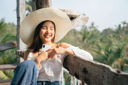 Cheerful asian woman smiling feeling happy after receive messages from friends or lover.の写真素材