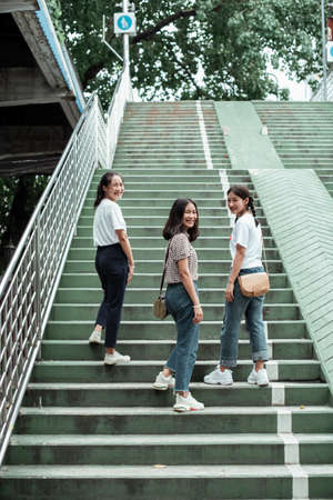Triple twin sister walking up the green stair in the park together.の写真素材