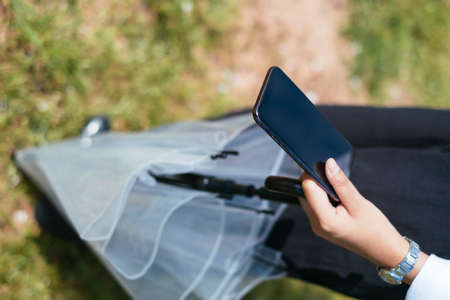 Closed up smartphone on hand and umbrella on woman legs.