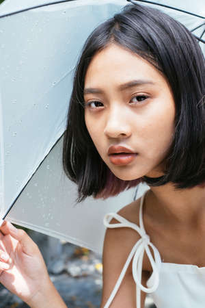 Close up of young thai woman holding white umbrella in garden park.の写真素材