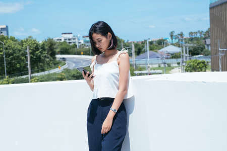Young thai teenager using mobile phone outside the building.