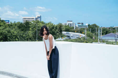 Sexy young asian woman leaning against white wall outdoor.