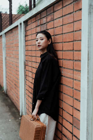 Black long hair woman in black shirt standing at the brick wall.の写真素材