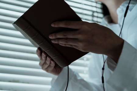 Cropped image of a book in woman's hand while she read it at the window.の写真素材