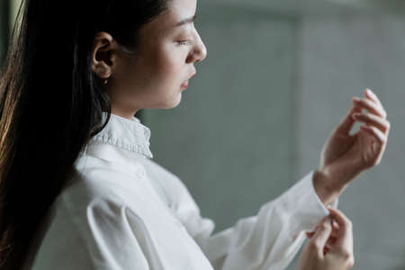 Black long hair woman touch the end of her sleeve.